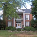 A red brick house with ways to keep the roof cool during the summers.