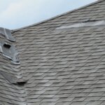 A shingled roof with a hole in it, attracting storm chasers.