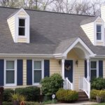 A yellow house with blue shutters and sidings.