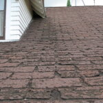 A brown tiled roof with a leaky shingle.