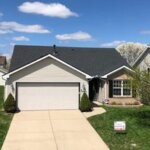 A suburban home with a garage and driveway suitable for retrofitting roofing.