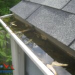 A roof with a clogged gutter and water on it.