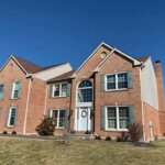 A brick home with a large front yard, perfect for installing a new roof.