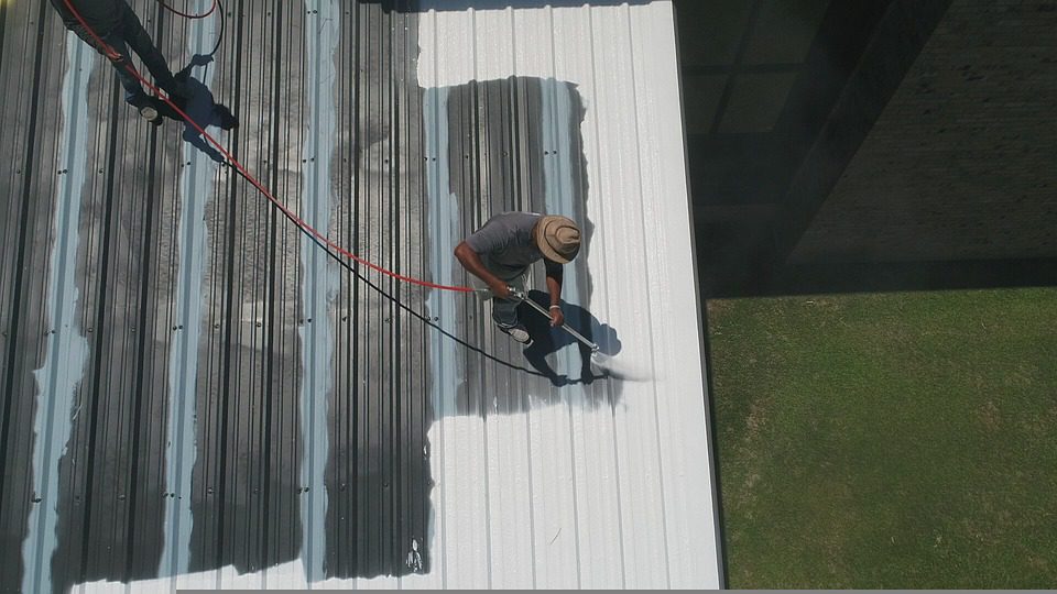 A man using a hose for commercial roof repair.