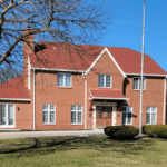 A red brick house with a flag in front of it, perfect for a roofing contractor.