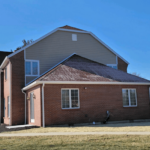 A brick house with a blue sky and questions to ask about the roof.