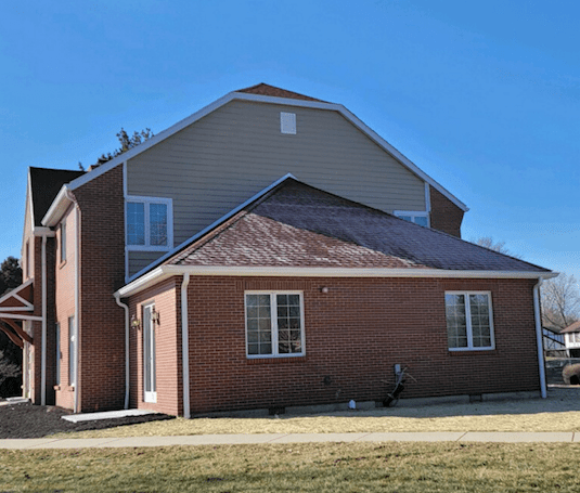 A brick house with a blue sky and questions to ask about the roof.