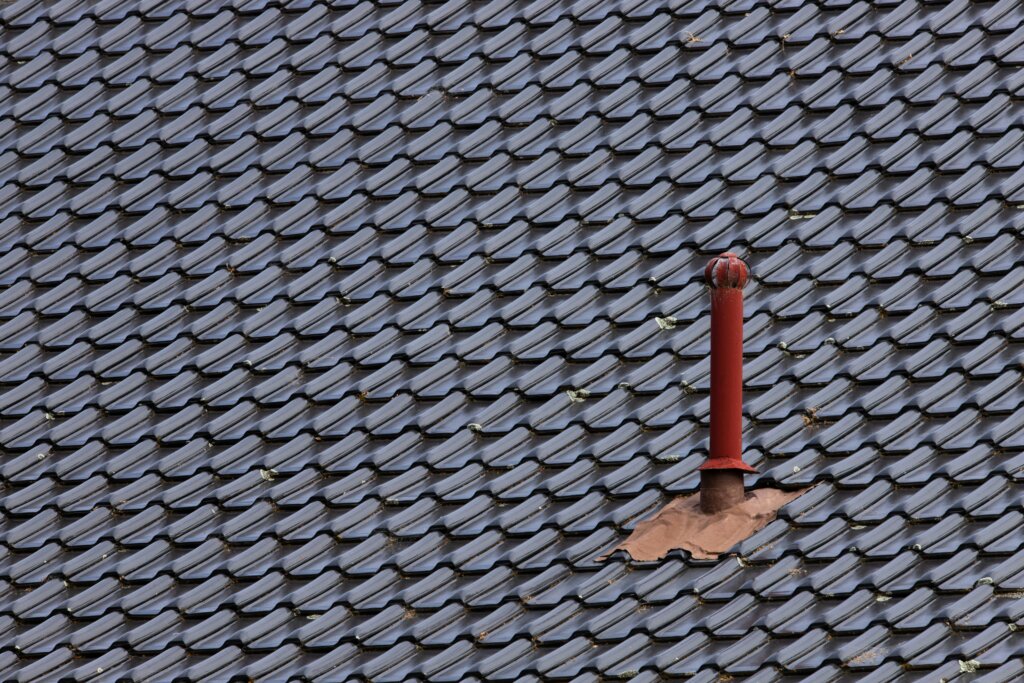 roof with metal gray shingles and a red spout