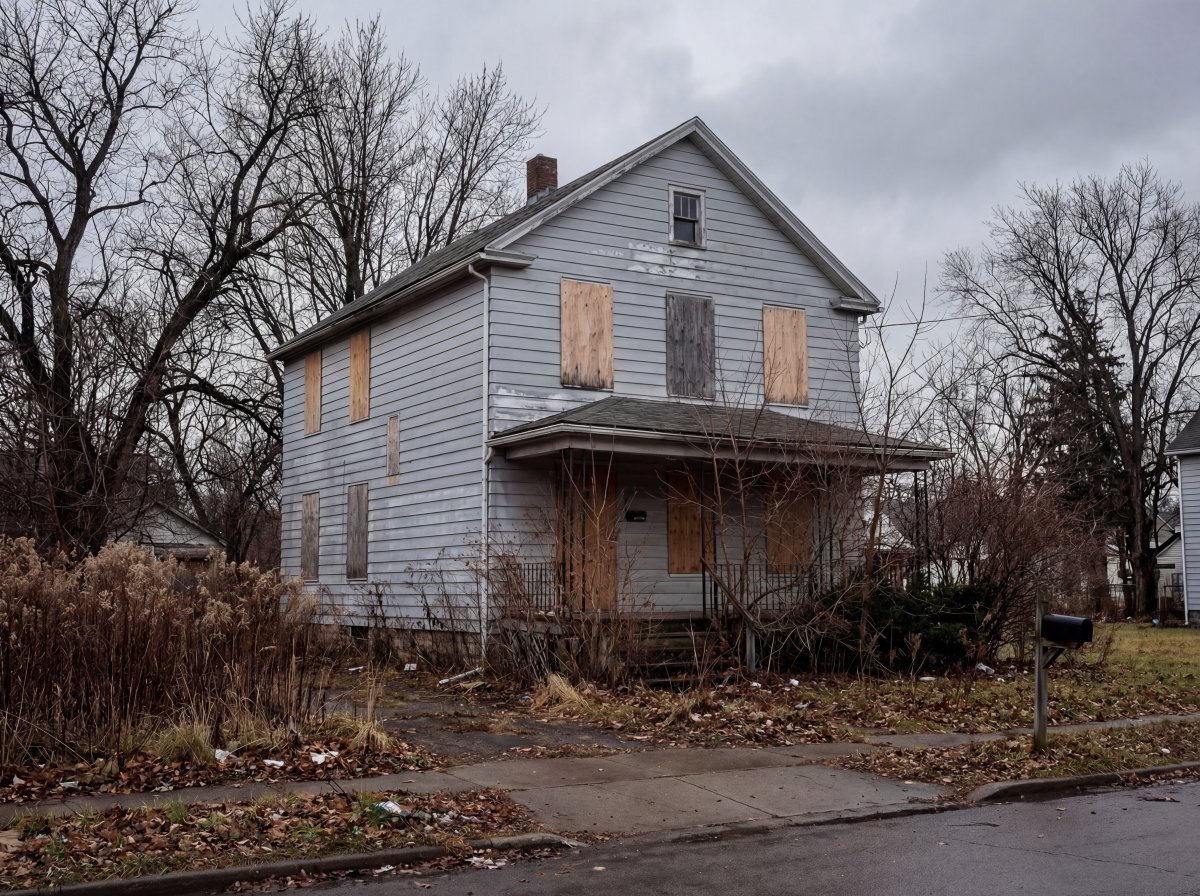 Vacant Buffalo NY home with boarded windows and overgrown yard — uninsured property triggering vacancy clause