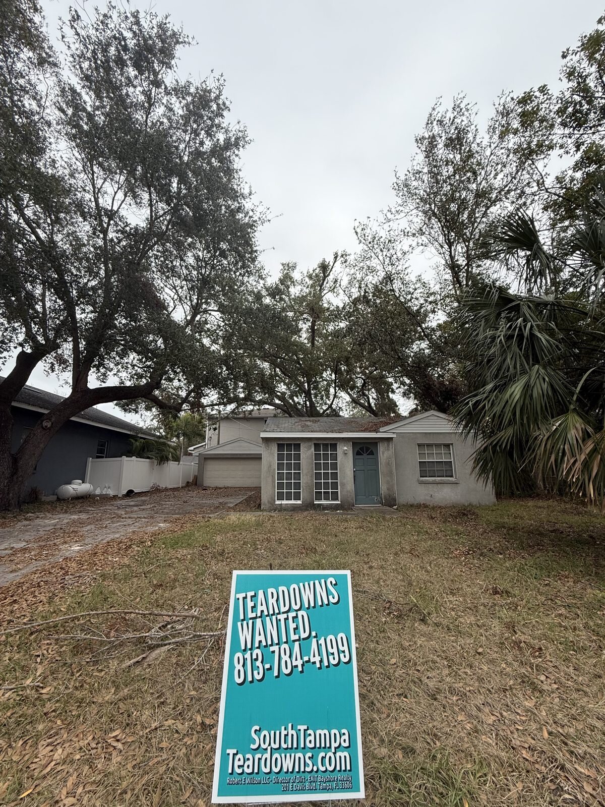 Older South Tampa house with a Teardowns Wanted sign under live oaks