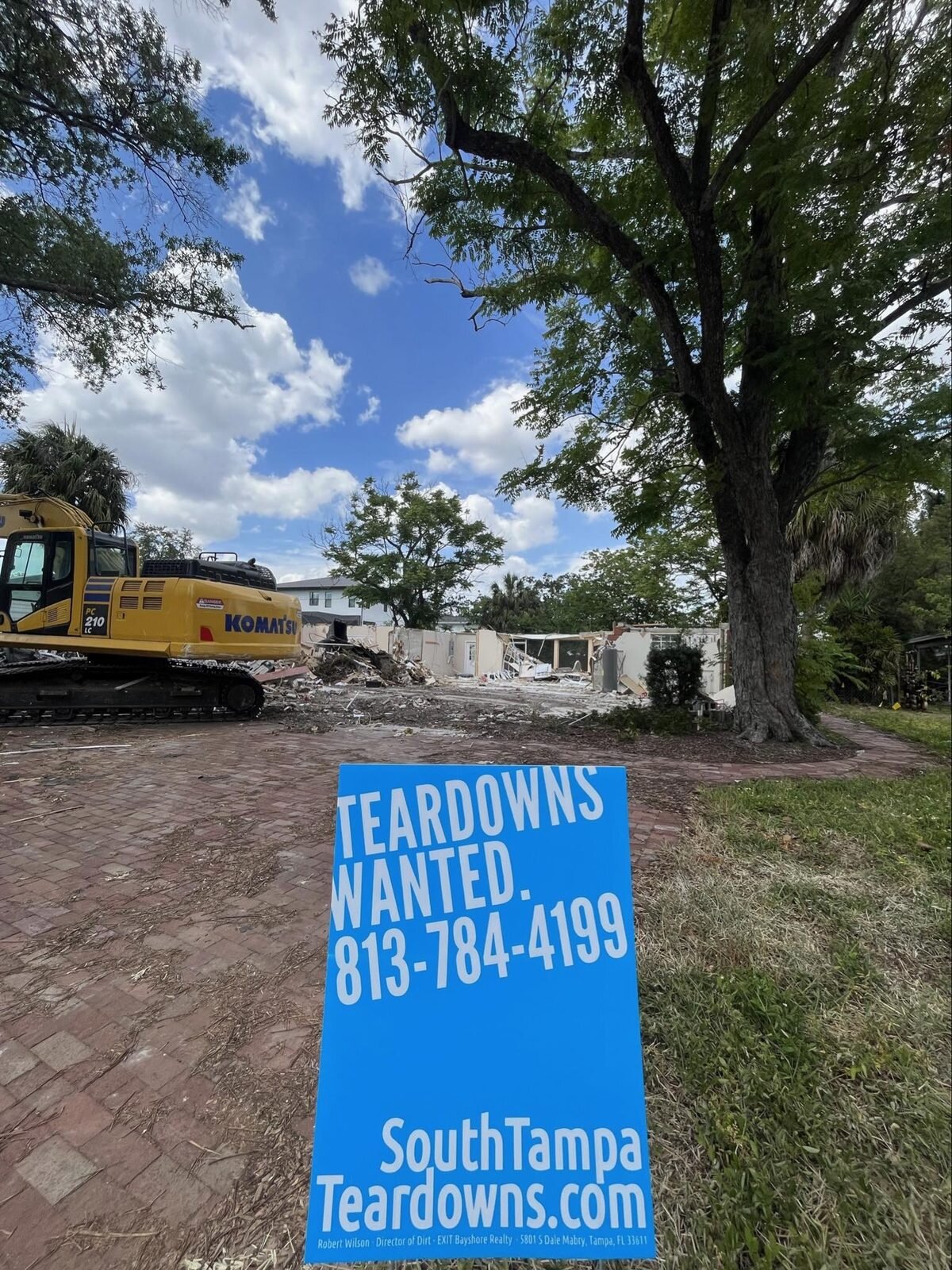 Excavator clearing an older South Tampa house with a Teardowns Wanted sign at the street