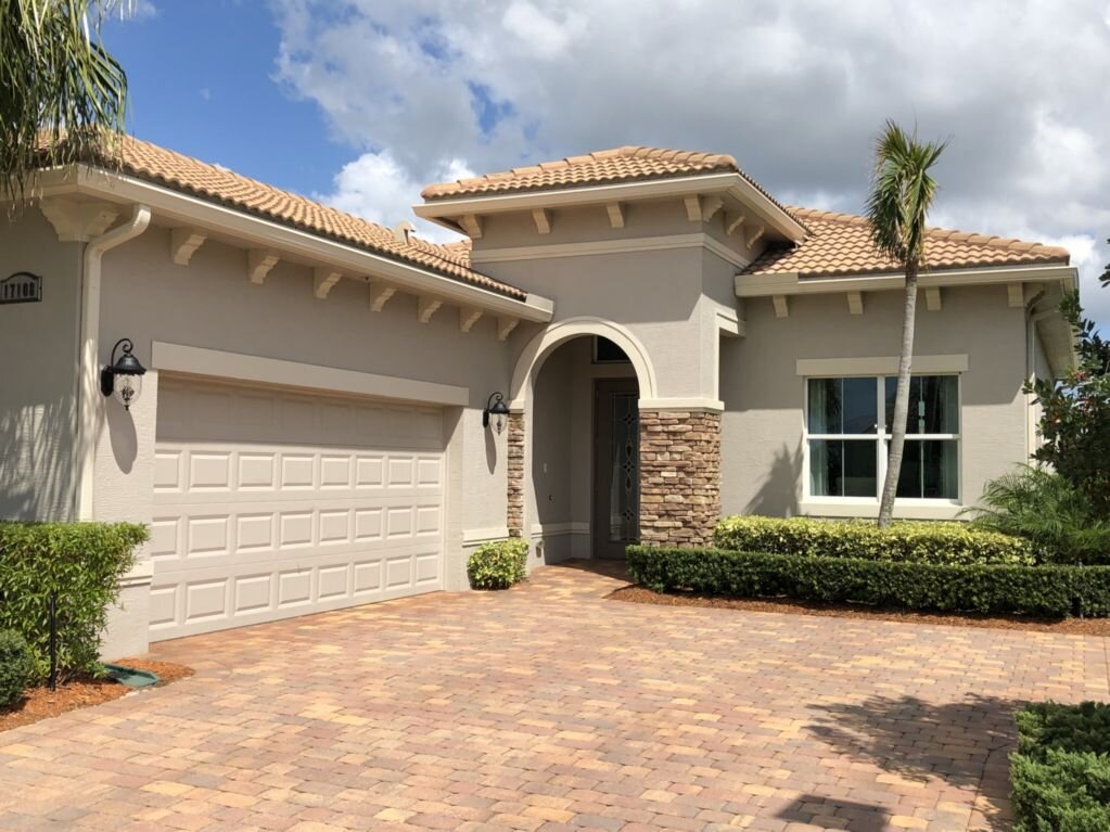 Spanish style home with roof, stone accents, and paver driveway.