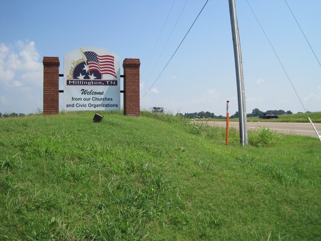 welcome sign with American and Tennessee flags beside a rural highway in Millington