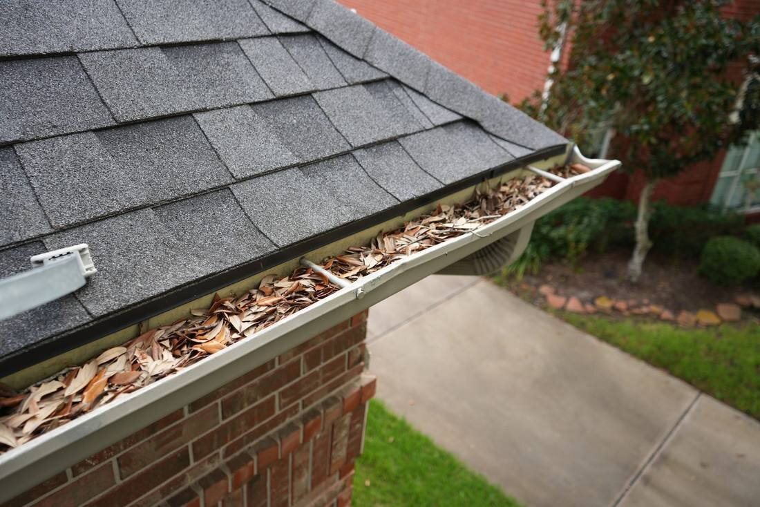 Leaf and debris buildup along a home roofline and gutter before cleaning in the Houston area