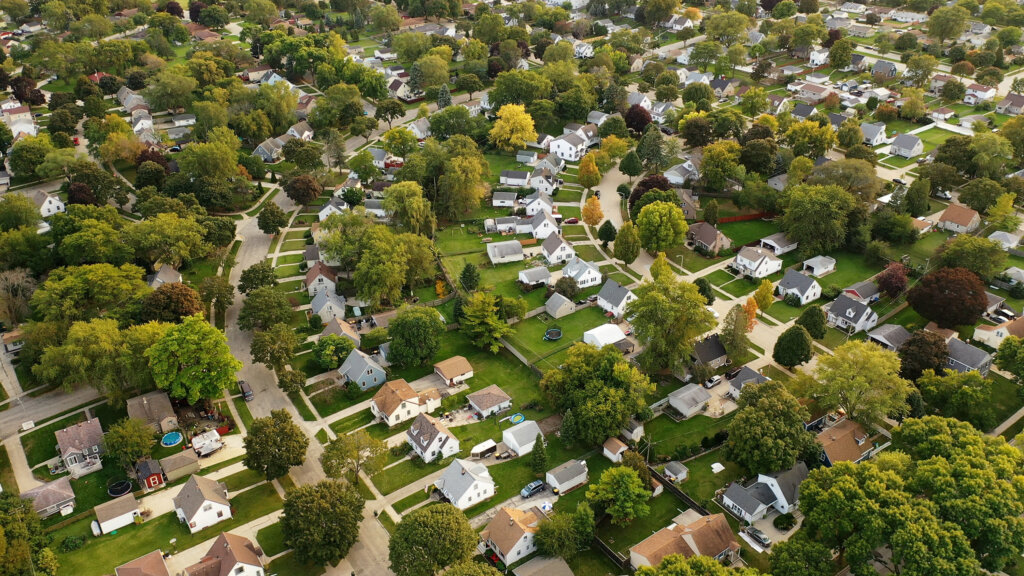 Aerial drone view of American suburban neighborhood at daytime. Establishing shot of America's suburb. Residential single family houses pattern
