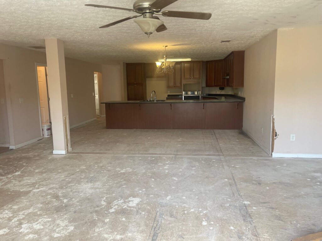 Interior of a dated Georgia home mid-renovation with no flooring and an outdated kitchen