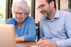Man helping Elderly Woman with laptop
