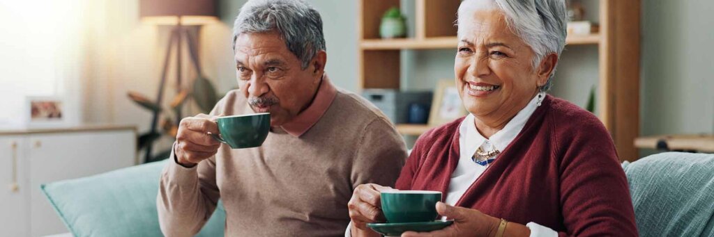 Happy Couple sitting on couch drinking coffee after Downsizing their Home