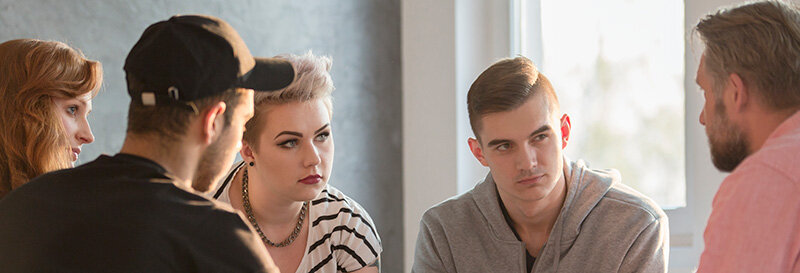 Siblings disagreeing on what to do with Mom's House sitting around the table looking at each other in serious discussion