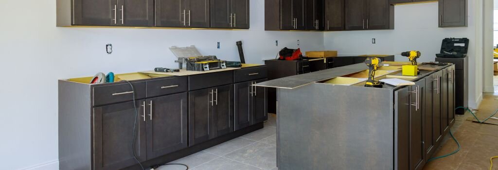 A kitchen mid-renovation with new cabinets installed and power tools on the counters, showing the scope of a full remodel in progress