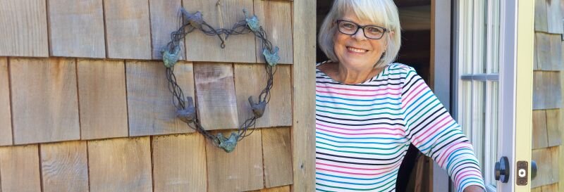 A woman smiling warmly outside a home, ready to help a family think through their next steps