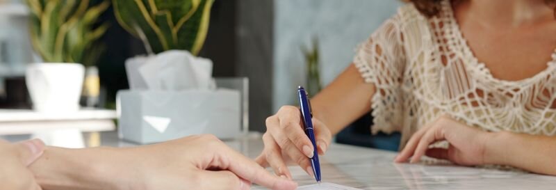 A woman reviewing documents with pen in hand, taking time to understand her options before making a decision