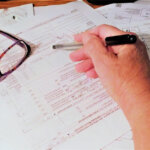 A Calculator and foreclosure sale documents on a table, hand pointing to a figure