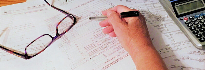 Calculator and foreclosure sale documents on a table, hand pointing to a figure FB
