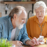 a Couple working through stack of mail including utility and tax bills on an cabinet top in the kitchen