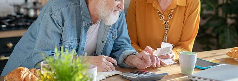 Couple working through stack of mail including utility and tax bills on an cabinet top in the kitchen