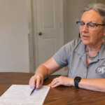 Becky explaining details to homeowner signing paperwork at a kitchen table