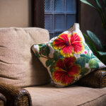 an Empty armchair by a sunlit window with a quiet interior, and pillow on armrest