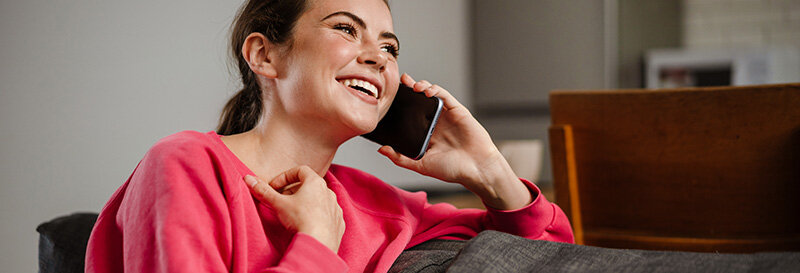 Woman laughing during a phone call, relieved and at ease no longer facing foreclosure