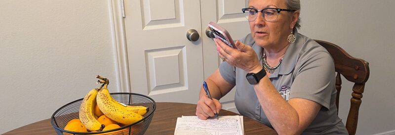becky sitting at kitchen table with fruit bowl talking to homeowner facing foreclosure filling out paperwork on the property