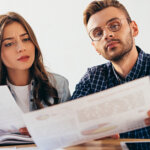 man and woman reviewing a real estate document together at a table with serious expressions in daylight
