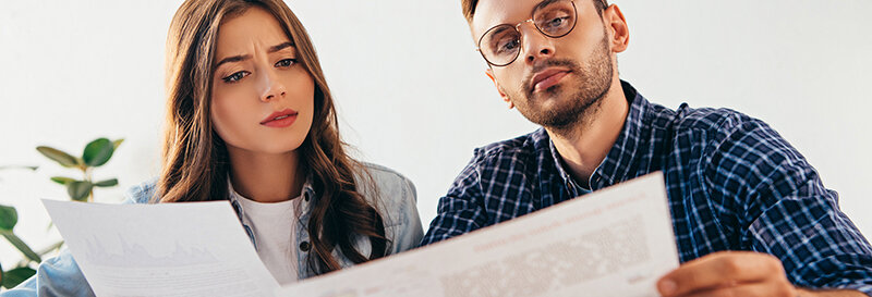 man and woman reviewing a real estate document together at a table with serious expressions