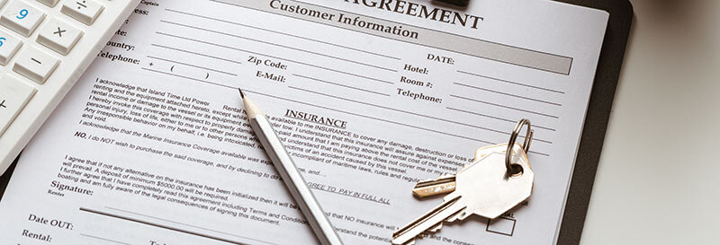 Signing a lease agreement with keys, calculator, pencil, and paperwork