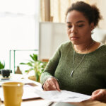 woman studying report at home with laptop on the table with coffee and pen