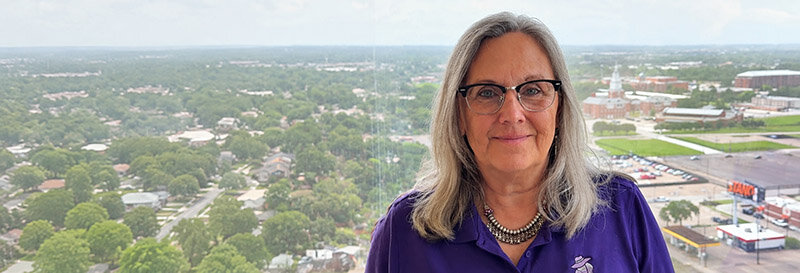 Becky Fields the Grandma who buys houses at her Houston office with Houston Christian University in the background through the window