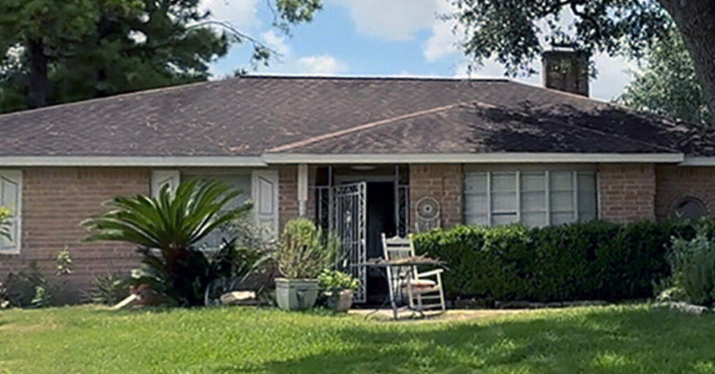 Brick Suburban Ranch House in Houston TX with white trim and rocking chair in front yard