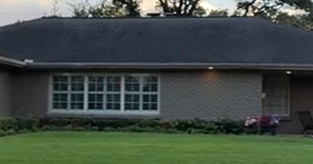 Dark green Brick Suburban Ranch House in Belleville TX with mowed front yard and short shrubs along front of house
