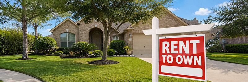 Light brown brick Houston house with landscaped front yard and arch windows and portal to front porch and two car garage on a sonny day with rent to own sign in front