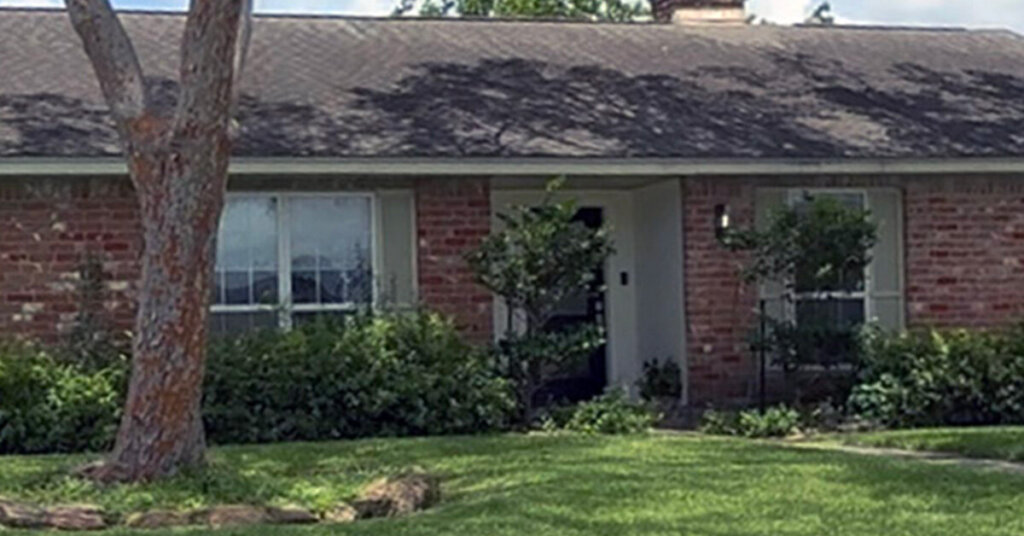 Red and white Brick Suburban Ranch House in Cypress TX with treee-covered front yard on sunny day