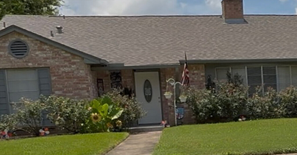 White and Red Brick Suburban Ranch House in Lake Jackson TX with blooming bushes and a manicured front yard