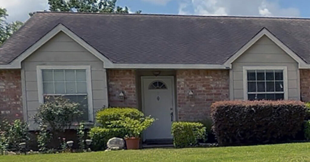 White and Red Brick Suburban Ranch House in Texas City TX with neatly trimmed blooming bushes and a manicured front yard