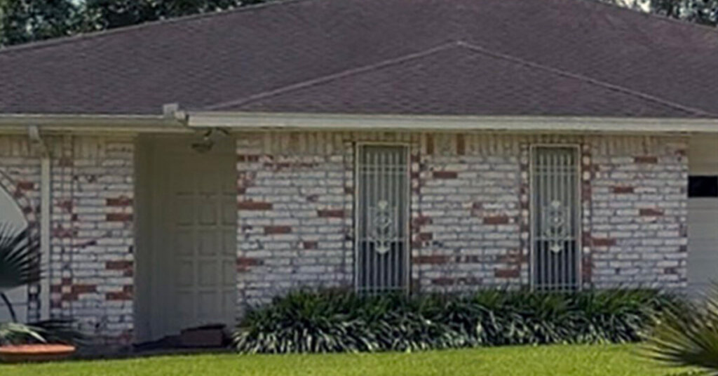 White and red Brick Suburban Ranch House in Katy TX with small shrubs in front