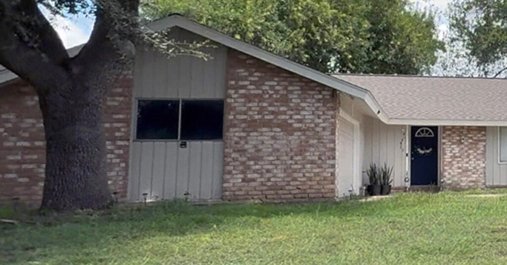 White and red Brick Suburban Ranch House in Liberty TX with large tree in yard on a sunny day