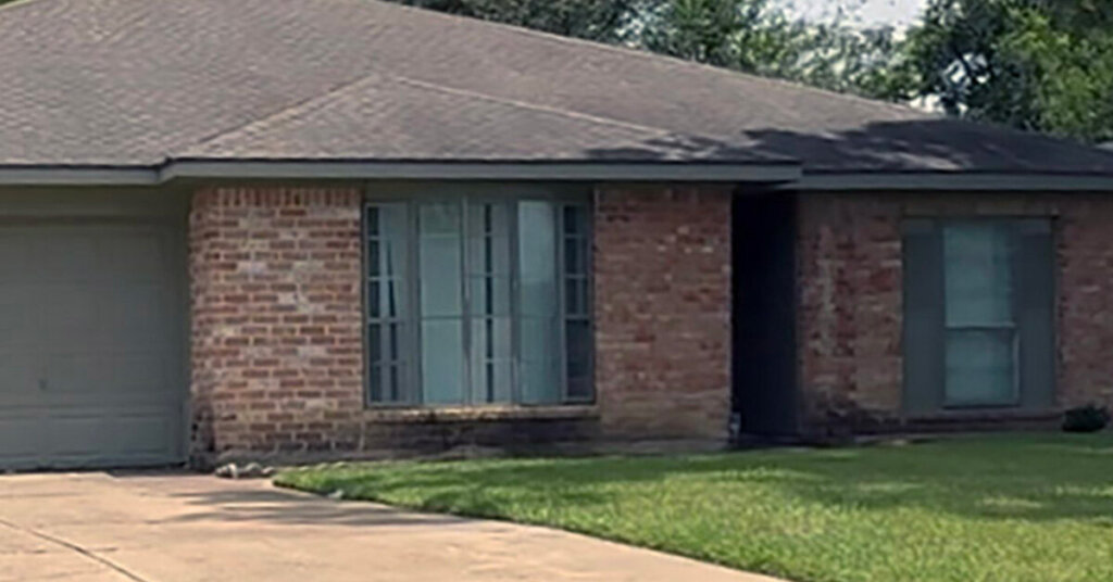 White and red Brick Suburban Ranch House in Pasadena TX with hip roof mowed front yard with no trees on sunny day