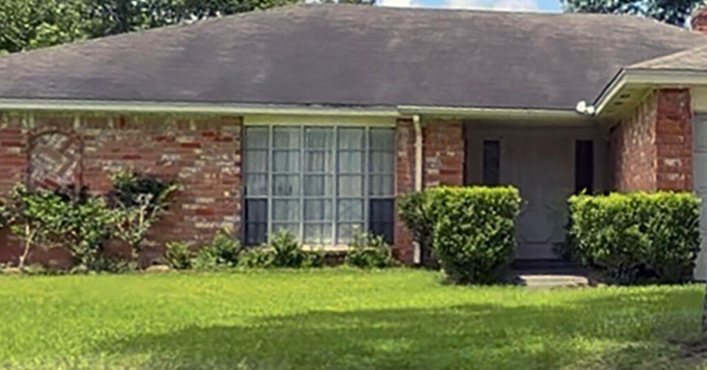 White and red Brick Suburban Ranch House in Wharton TX with hip roof mowed front yard with no trees on sunny day