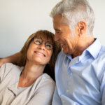 a loving couple embracing each other on couch benefiting from knowledge of property capital gains